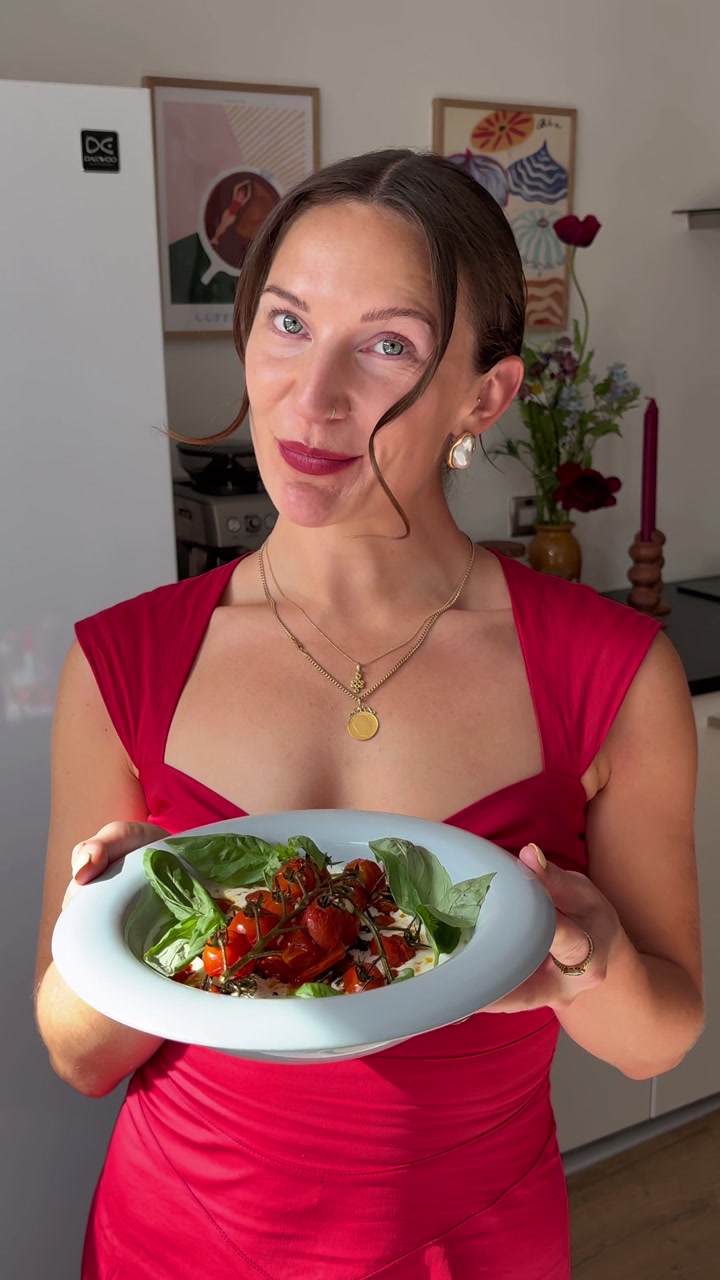 Jade holding a plate of roasted tomatoes and burrata in her kitchen
